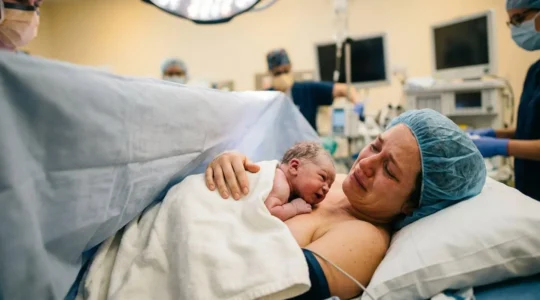 Mère tenant son nouveau-né en peau à peau dans un environnement hospitalier chaleureux avec équipe médicale bienveillante