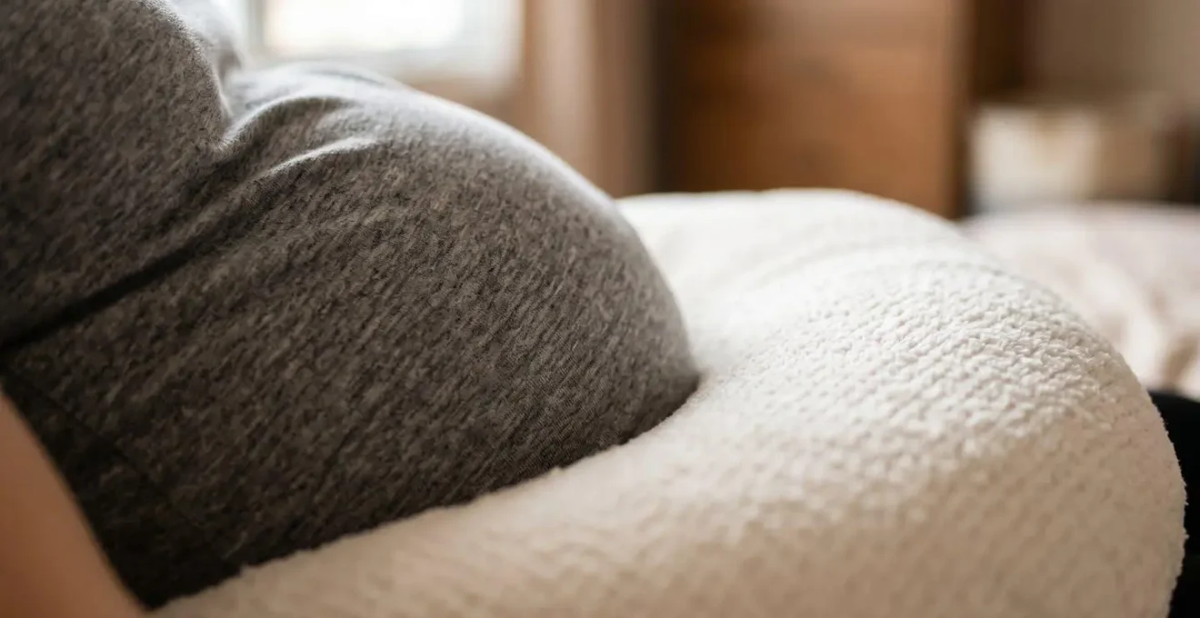 Gros plan sur le ventre arrondi d'une femme enceinte délicatement soutenu par un coussin moelleux
