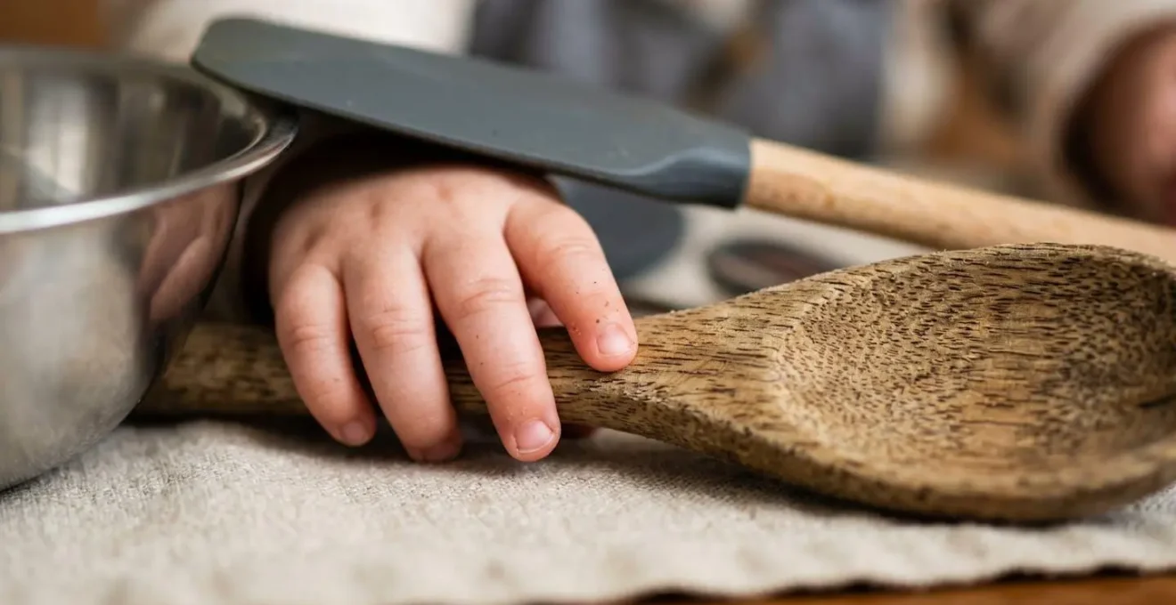 Bébé manipulant des ustensiles de cuisine en bois et inox sur un tapis