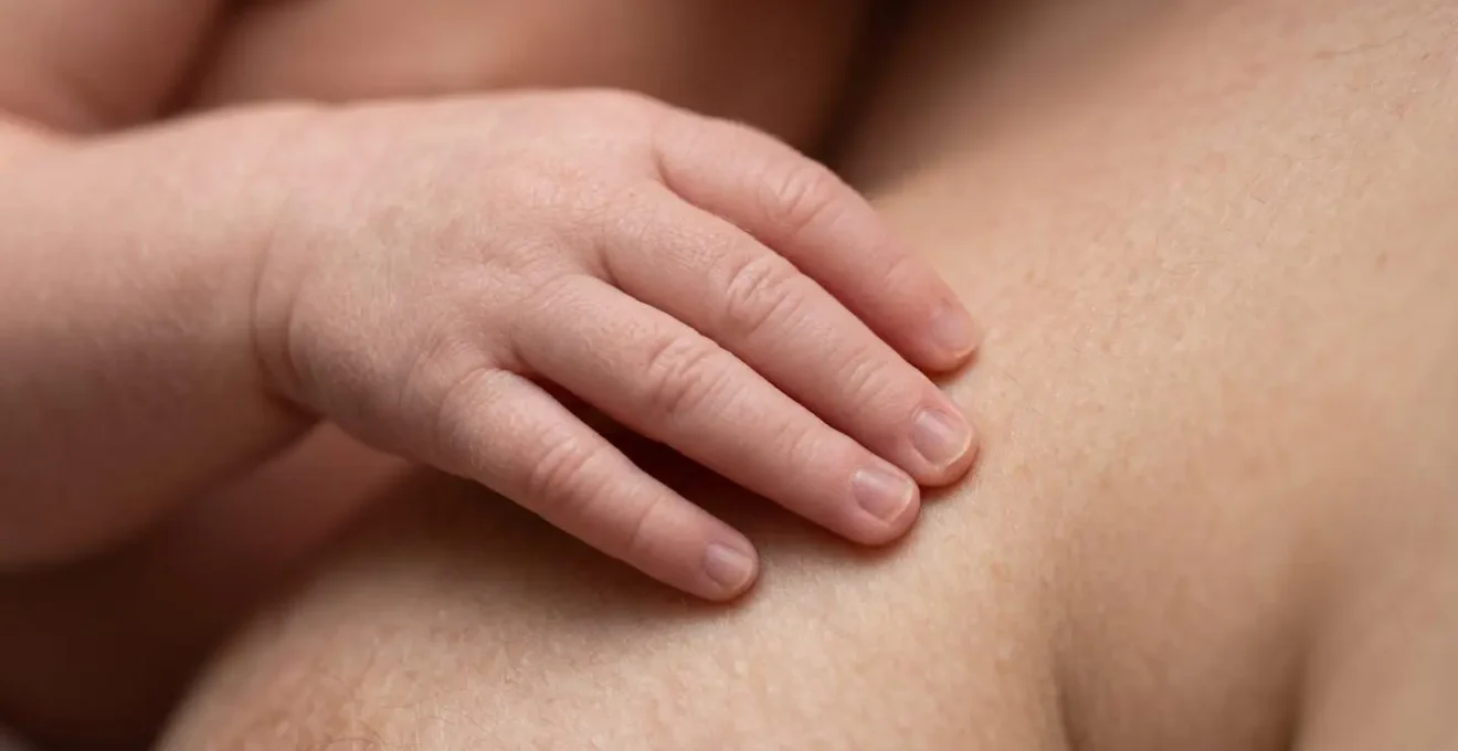 Très gros plan sur la main minuscule d'un nouveau-né posée sur la peau du parent, détails des textures de peau