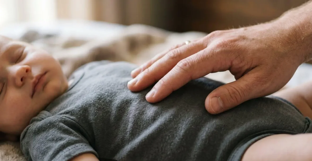 Main posée délicatement sur le ventre d'un bébé endormi pour compter sa respiration